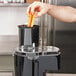 A person using a Waring food processor to shred carrots.
