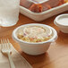 A white compostable plastic lid on a bowl of food with a plastic fork.