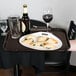 A brown Cambro Polytread non-skid serving tray with food and wine on a table.