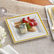 A Visions ivory plastic square plate with gold bands holding cheese and grapes.