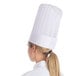 A woman wearing a white Royal Paper disposable chef hat.