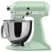 A KitchenAid pistachio green countertop mixer with a bowl on top.