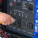 A person using a power cord to plug a DuroMax XP15000E generator into a yellow outlet.