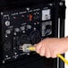 A hand plugging a yellow cable into a DuroMax XP12000E generator.