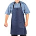 A man wearing a Uncommon Chef indigo denim bib apron with black webbing.