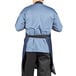 A man wearing a Uncommon Chef denim bib apron with black webbing.