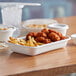 A white Eco-Products compostable takeout container with food inside on a table.