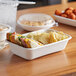 A white Eco-Products compostable takeout container with food inside on a table.