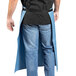 A man wearing a Uncommon Chef blue and gray canvas apron with black webbing over a black shirt and blue jeans.