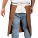 A man wearing a Uncommon Chef brown canvas waist apron with natural webbing.