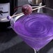 A violet cocktail with Spirdust shimmer on top and a cherry.