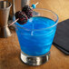 A blue cocktail with blackberries on a stick.