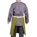 A man wearing a moss green Uncommon Chef Vibe apron with natural webbing.