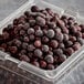 A plastic container with black berries.