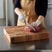 A person cutting meat on a Fox Run acacia wood chopping block.