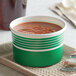 A green Choice paper bowl filled with soup on a tray.