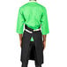 A man wearing a black Uncommon Chef Vibe bib apron with green accents.