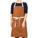 A woman wearing a customizable Uncommon Chef canvas bib apron with pockets.