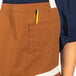 A person wearing a Uncommon Chef walnut canvas bib apron with a pencil in the pocket.