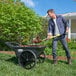 A man using a Rubbermaid big wheel cart to shovel dirt.