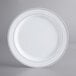 A white plastic plate with silver bands.