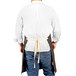 A man wearing a dark brown Uncommon Chef canvas bib apron with natural webbing.
