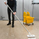 A woman using a Carlisle Sparta stainless steel pole to clean the floor.