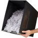 A person holding a black box with shredded paper.