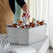 A person pouring juice into an American Metalcraft galvanized metal beverage tub.