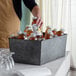 A person pouring juice into an American Metalcraft galvanized metal beverage tub.