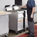 A man in a black apron using a Frymaster liquid propane floor fryer in a commercial kitchen.