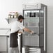 A man in a black apron putting trays in a Beverage-Air reach-in freezer in a professional kitchen.