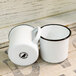 Two white Crow Canyon Home enamel mugs with black rims.
