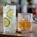 Two Acopa Madras rocks glasses filled with a whiskey drink on a wooden table.