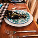A table set with Crow Canyon Home vintage white enamelware plates and silverware.
