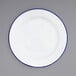 A white Crow Canyon Home enamelware plate with a blue rim.