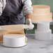 A person using a rolling pin to make a cake dummy.