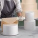 A person using a rolling pin to roll out Baker's Mark round cake dummies.