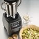 The base of a Waring food blender next to a bowl of salad with lettuce and nuts.