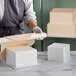 A woman using Baker's Mark foam to make a large square cake.