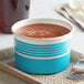 A blue Choice paper cup filled with soup on a tray.