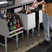 A man pouring drinks into a Regency underbar ice bin.