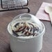 A clear plastic cup of frozen yogurt with a clear dome lid on a counter.