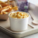 A tray with a Choice white paper cup filled with macaroni and cheese and fries.