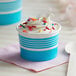 A blue and white paper cup filled with ice cream and sprinkles.