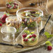 A clear plastic container with a lid on a table with a fork and food inside.