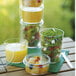 A stack of Solia clear plastic cups filled with fruit salad on a table.