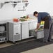 A man putting food into a drawer in an Avantco undercounter refrigerator.