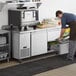 A man preparing food on an Avantco stainless steel worktop refrigerator with drawers in a professional kitchen.