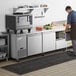 A man opening an Avantco stainless steel undercounter refrigerator with drawers and doors.